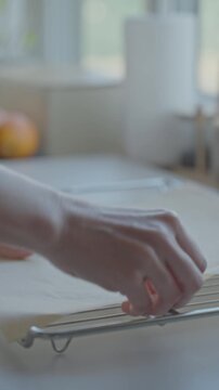 Hands place wire rack on table and cover it with parchment paper for baking