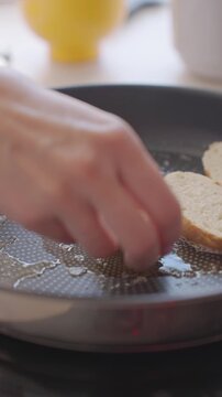 Hand places bread slices in frying pan with melted butter