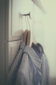 Two shirts on coat hangers hanging on a wardrobe hook