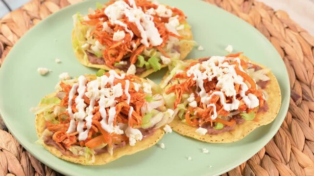 Homemade tostadas de tinga close-up served on a green plate. The plate is rotating slowly