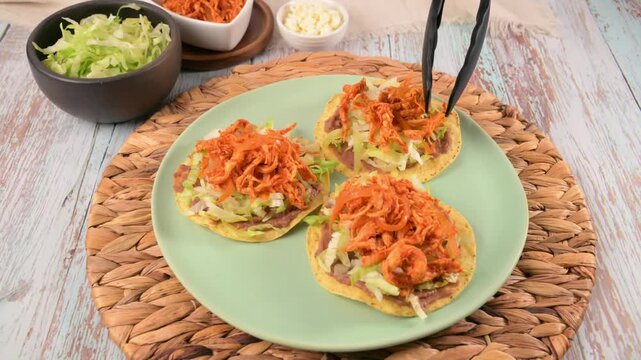 Mexican Chicken Tostadas Preparation. Hand prepares a Mexican tostada with chicken tinga