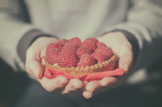 Close-up of a mature Woman holding an individual  Raspberry Tart