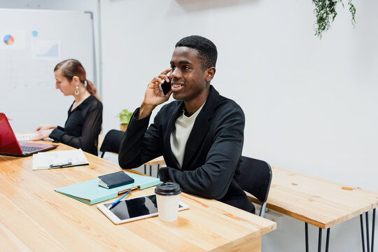 Young business african american man using phone and talking in call at office or workplace in Latin American