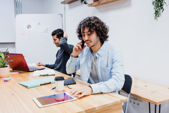 young hispanic businessman talking by phone in a call at office in Latin America, latin male working at workplace 