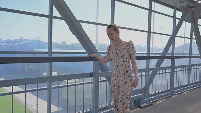 A Caucasian woman with cerebral palsy walks across a pedestrian bridge.