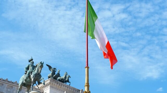 Italian flag waving at altar of the fatherland in rome. National italian flag waving in the wind against a blue sky with the quadriga of unity statue on the altar of the fatherland in rome