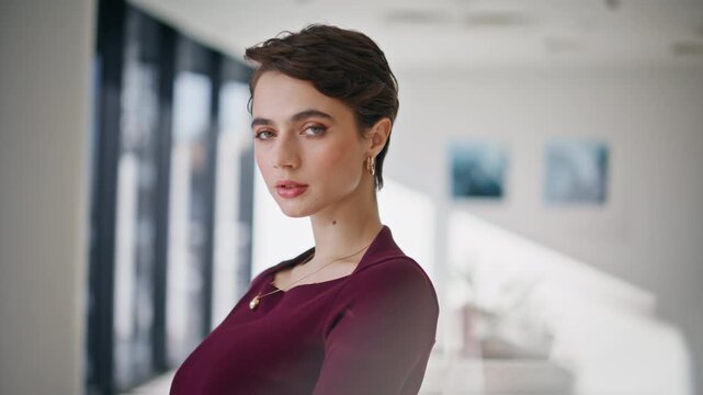 Businesswoman turning head close up. Pixie lady posing modern gallery interior.