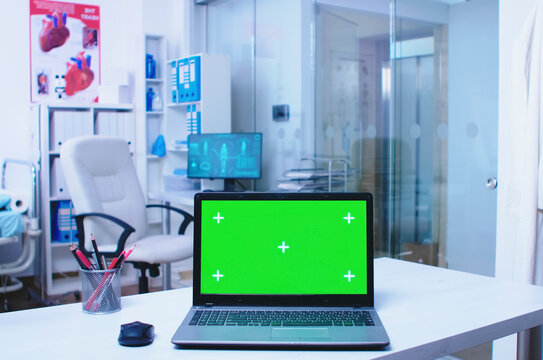 Laptop with green screen in a hospital cabinet, showing nurse movement, glass door activity and editable laptop screen space for healthcare technology.