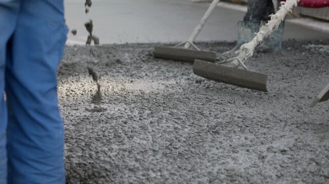 Leveling fresh concrete with screed board during concrete pouring
