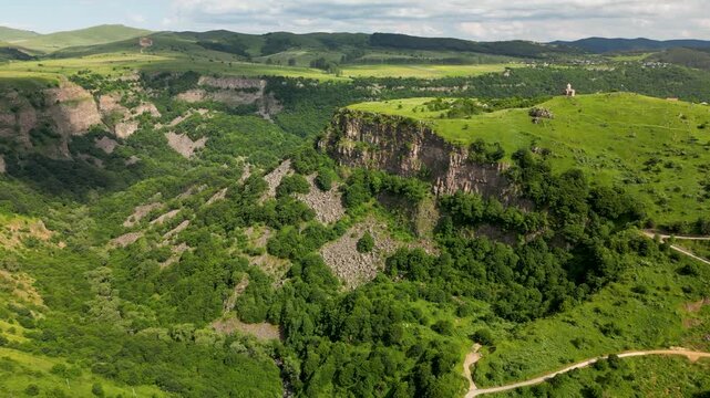 Aerial drone footage of a small church overlooking Dashbashi Canyon in Georgia surrounded by scenic landscape and rolling hills.