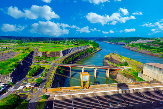 Panoramic view of the Itaipu Hydroelectric Dam on the Parana River, showing the massive engineering structure, surrounding green landscape, and blue sky on the border of Brazil and Paraguay.