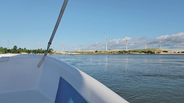 Green infrastructure by the sea: Large wind farm on sand dunes viewed from a river boat cruise.