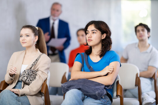 Mature male lecturer in background of classroom, address to youth listeners. Personal growth courses, professional orientation, overview lecture about educational institutions