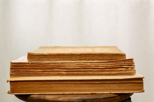 A stack of old books. A collection of antique books neatly arranged on a wooden shelf against a white background. Conceptual themes of history, nostalgia, and old age. Retro style.