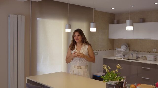 Woman drinking water and smiling in a modern kitchen