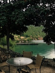Fototapeta premium Cozy Lakeside Cafe Terrace with Table and Chairs Overlooking Scenic Turquoise Lake 