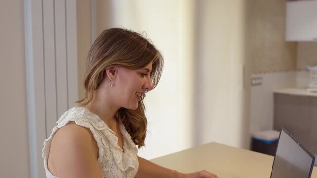 Smiling young woman working remotely at home on her laptop