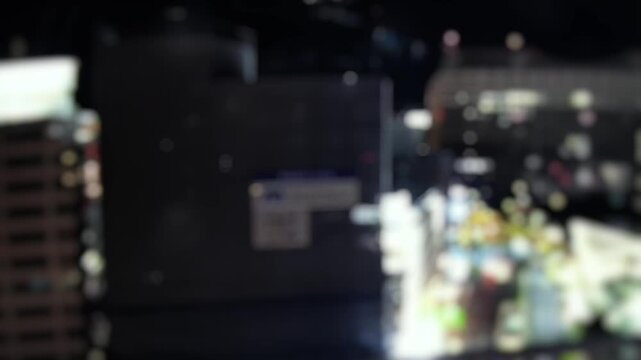 Abstract defocused time lapse of urban night lights and buildings in Naha Okinawa Japan. Soft bokeh cityscape background for motion and nightlife concepts.