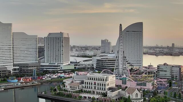 Timelapse of Yokohama waterfront cityscape with modern buildings and harbor at dusk in Japan. Urban lights begin to glow over the bay.