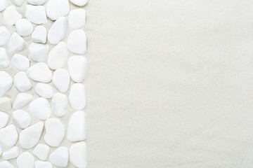 White pebble stones with sand as background, top view © Liami