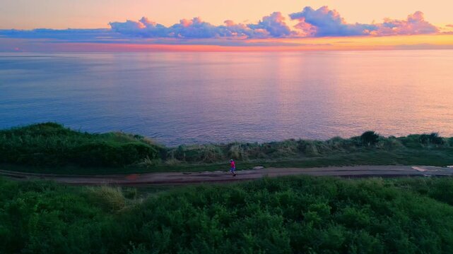 A senior adult jogs along a serene coastal path as the sun sets, reflecting on calm ocean waters, emphasizing tranquility and dedication to a healthy lifestyle.