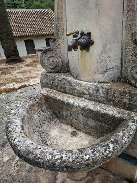 Antique stone drinking fountain with a brass tap at the historic San Francisco de Borja leprosarium in weathered condition