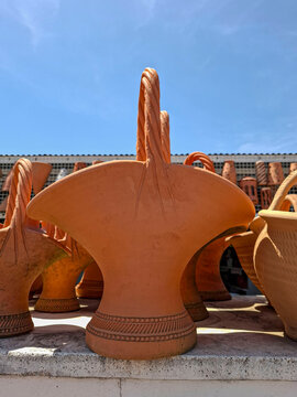Close up of terracotta clay basket with twisted handle showing texture of handmade traditional pottery