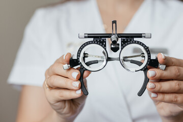 Close-up of ophthalmologist holding trial frame for visual acuity testing in an eye care clinic. Professional optometry equipment used for vision diagnostics and prescription lenses. © Валерия Стоганенко