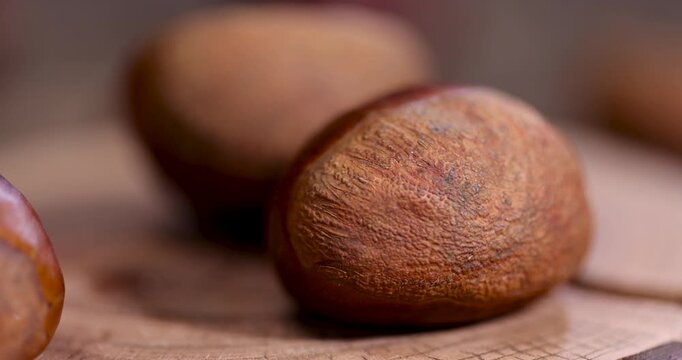 Edible harvested chestnuts, a group of large fresh chestnuts harvested and scattered on an old wooden table during cooking and cooking, forest product