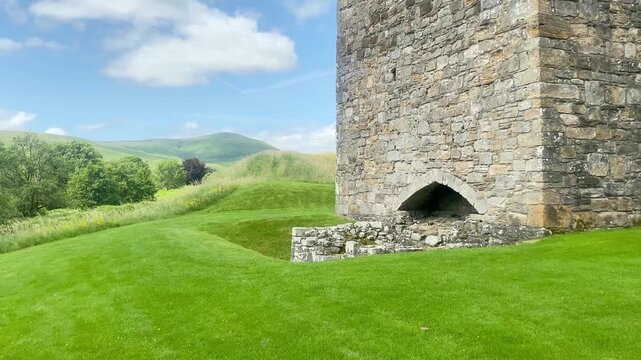 Close up view of the massive stone corner tower and dry moat of Hermitage Castle in Scotland