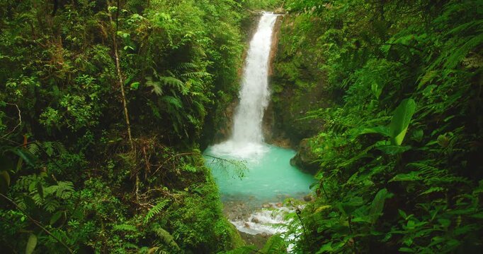 Tall Costa Rica waterfall dropping into a turquoise pool in lush tropical forest