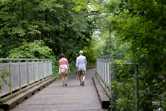 Un couple marchant sur un pont dans le parc urbain bois&eacute;.	
