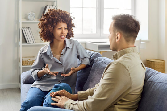 talking on sofa at home, conversation. Focused woman talks while man listens in a cozy living room, expressing trust, empathy and care. Clear concept is communication at home.