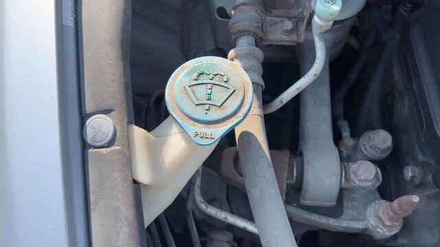 Windshield washer fluid reservoir cap in car engine bay close up