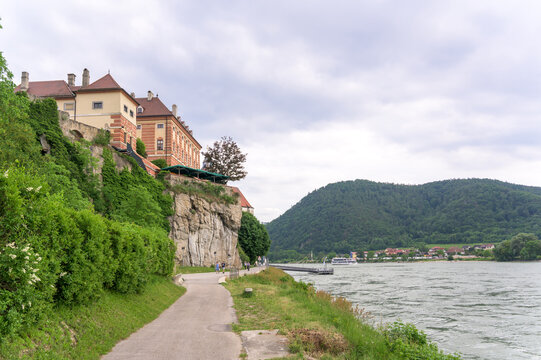 A scenic view of Hallstatt, Austria showcases a tranquil lakeside path lined with lush greenery