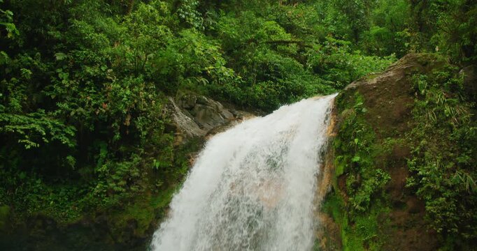 Powerful waterfall plunging over mossy cliff surrounded by thick jungle in Costa Rica