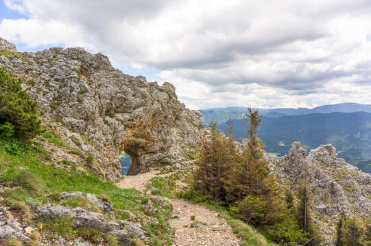 A breathtaking view of a rocky landscape at Rax Austria featuring lush greenery under a dramatic cloudy sky