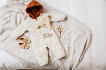 Fototapeta premium Cozy baby winter outfit with quilted jumpsuit, knitted hat, moccasins, and wooden toys on a soft blanket