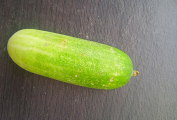 top view of a single fresh green cucumber on a dark textured background © Birul Sinari-Adi