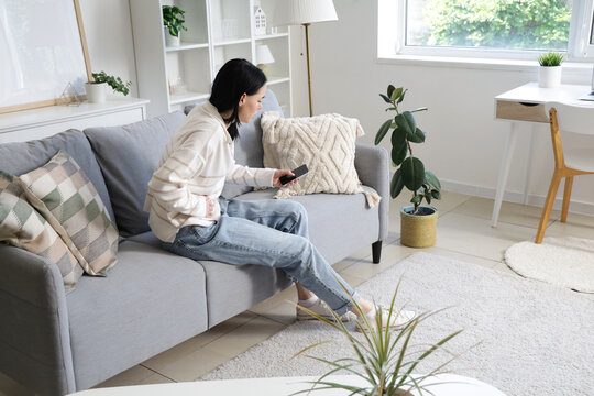 Young woman with severe abdominal pain calling an ambulance at home