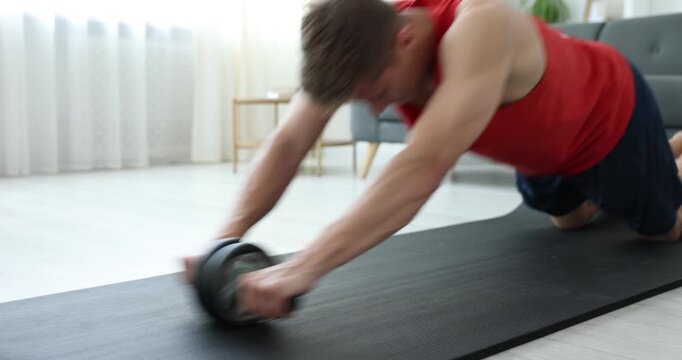 Man exercising with ab roller on fitness mat at home