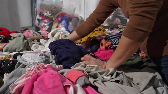 Woman digging through pile of discarded clothes fast fashion waste problem