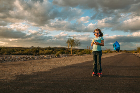 Girl holding balloon standing on desert path