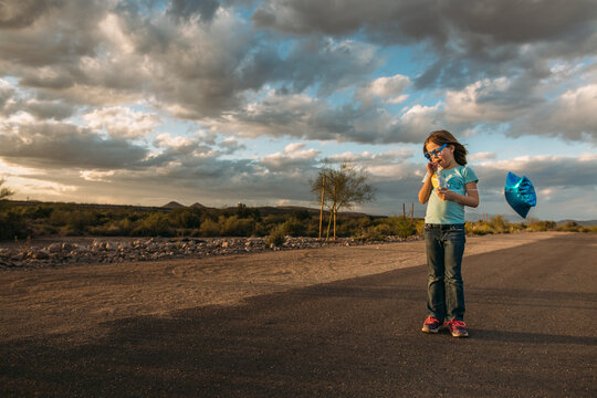 Girl with balloon standing on desert path