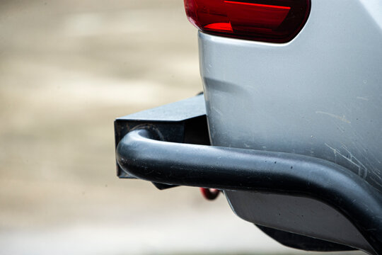 Close-up of a silver car's rear bumper with a black steel off-road bull bar.   A detailed close-up shot capturing the rear corner of a silver pickup truck or SUV vehicle. 