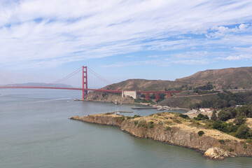 Fototapeta premium Golden Gate Bridge extending across San Francisco Bay, anchoring a historical landmark linking San Francisco with Marin County, surrounded by hills and calm waters on a clear day