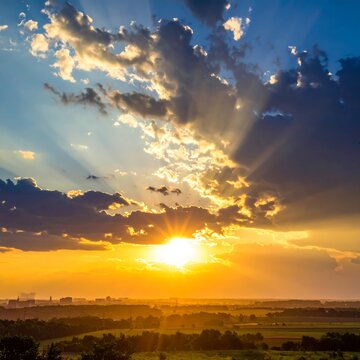 Vibrant sunset casting golden sunbeams through dramatic clouds over landscape