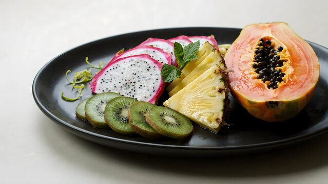 Fresh sliced tropical fruit platter with papaya pineapple kiwi and dragon fruit