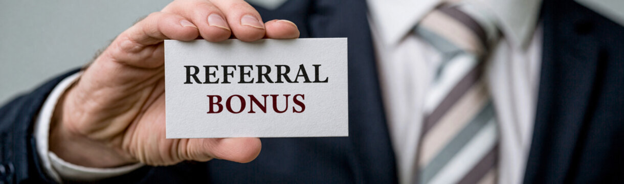 Referral Bonus Opportunity: A sharply dressed businessman in a striped tie holds up a card announcing 'REFERRAL BONUS', symbolizing a reward for recommendation and client acquisition.