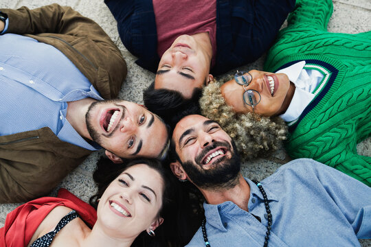 Young diverse people having fun together outdoor lying in circle - Focus on right guy face